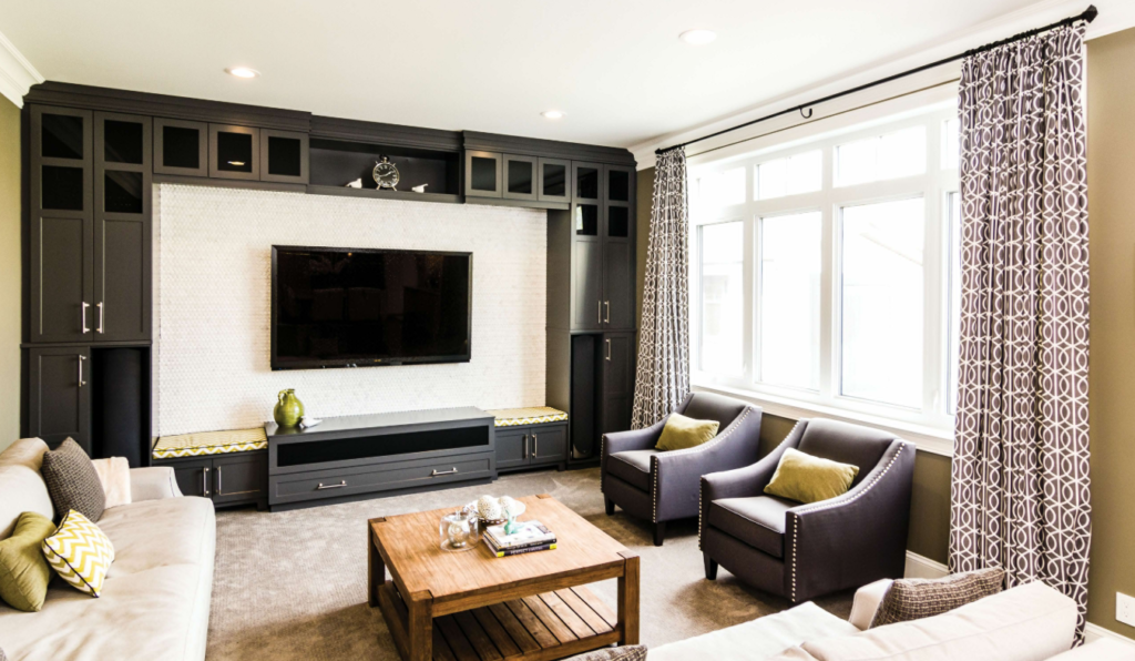 Family Room vs Living Room Decorating Ideas Stylish living room showcasing layout differences for comfort versus conversation, with a beige sofa, dark armchairs, built-in entertainment center, and natural lighting